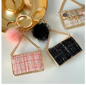 Detail of tweed mini bag keychains with gold chains, camellia charms, and fluffy fur balls