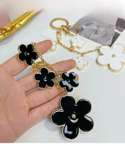 Detailed close-up of a black enamel flower keychain with gold-plated chain and lobster clasp