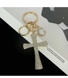 Detailed macro view of a gold cross keychain with rhinestones and a crystal drop