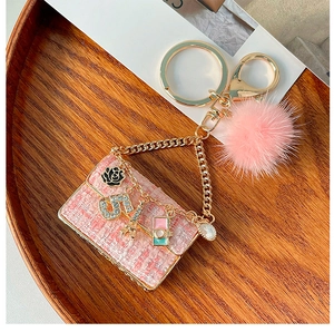 Detail of pink tweed mini bag keychain with faux fur pompom and golden Eiffel tower charm