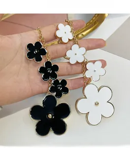 Close-up of elegant floral keychain with black and white enamel flowers and gold beads