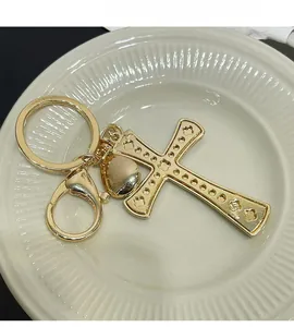 Detailed view of a gold-plated cross keychain with intricate textures on a white tray
