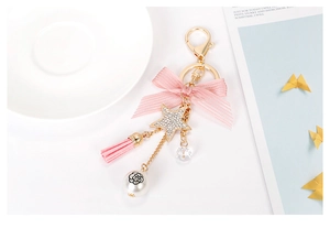 Detailed view of a pink bow keychain with tassel, star pendant, and floral faux pearl