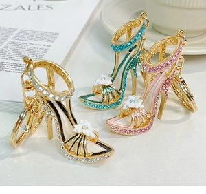 Detail von High-Heel-Schlüsselanhängern mit Strasssteinen und weißen Emailleblumen