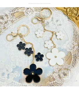 Detail of floral keychain with black and white enamel camellia flowers and golden hardware