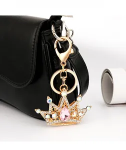 Detailed close-up of a crystal crown keychain with pink rhinestones on a black leather bag