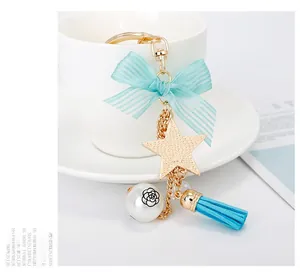 Detail of star keychain with blue bow, floral pearl, and suede tassel on a cup