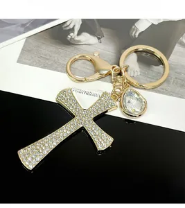 Macro shot of gold cross keychain with rhinestones and a pear-shaped crystal charm