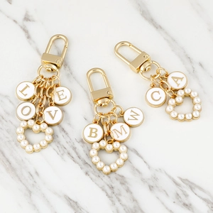 Golden metal keychain with pearl heart pendant and white enamel letter charms