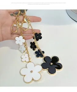 Detailed close-up of black and white enamel camellia flower keychains with gold clasps
