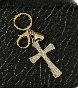 Detail of a sparkling crystal cross keychain with gold metal heart charm on black leather