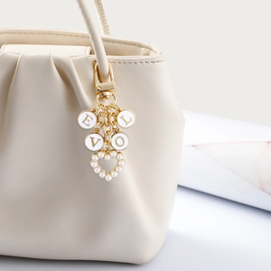 Golden heart pearl charm keychain with LOVE letter pendants on white leather bag