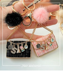 Close-up of pink and black tweed mini bag charms with camellia and fur ball pendants
