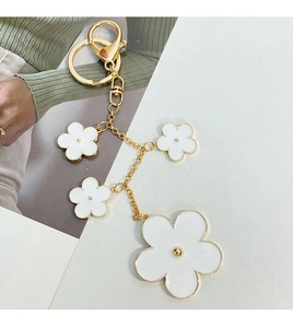 Detailed close-up of white clover flower charms on a golden metal keychain hanger