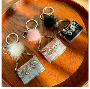 Macro shot of tweed mini bag keychains with plush pompons and gold charms on wood