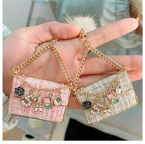 Close-up of pink and beige tweed bag charms with gold chains and camellia charms