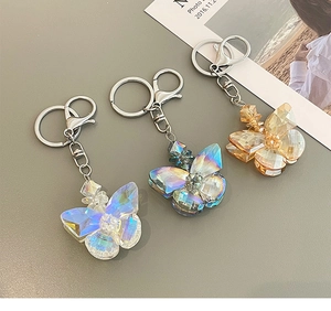 Three faceted crystal butterfly keychains in iridescent white, blue, and gold finishes