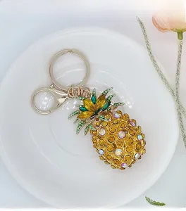 Close-up of a pineapple keychain with golden and green crystals on a white plate