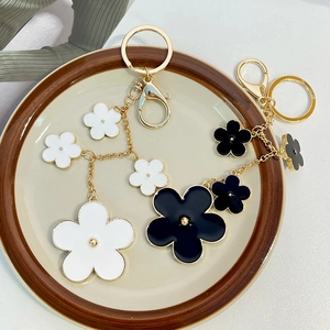 Elegant floral keychain featuring black and white camellia charms with gold plating