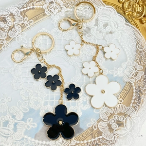Elegant floral keychain featuring black and white enamel camellia petals with gold metal chain