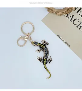 Close-up of a gold-plated lizard keychain with sparkling green and grey rhinestones