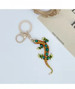 Detail of lizard keychain with green rhinestones and orange enamel on golden metal