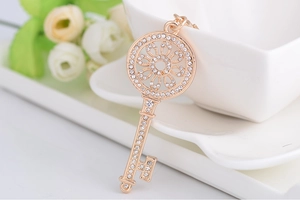 Gros plan du pendentif clé en or rose serti de strass brillants sur un fond floral élégant