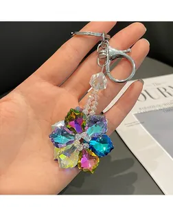 Close-up of a colorful crystal flower keychain with silver lobster clasp held by a hand