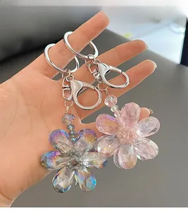 Detailed macro view of colorful and pink crystal five-petal flower keychains with silver clasp