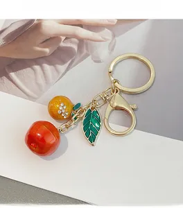 Detail of metal keychain with red cherry, orange fruit and green leaf charms