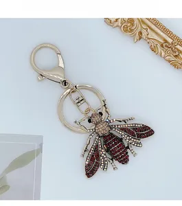 Detail of bee keychain with red rhinestones and gold alloy lobster clasp on white background
