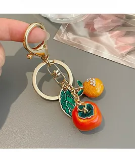 Detail of persimmon keychain with gold ring, green leaf and rhinestone fruit charm