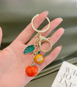 Detail of creative orange and persimmon fruit keychain with sparkling rhinestones and gold ring