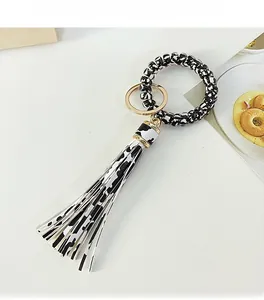 Detail of a cow print leather tassel and golden keyring with elastic telephone wire wristband