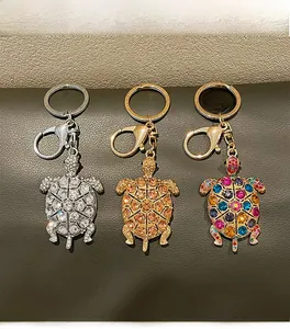 Dettaglio di tre portachiavi a forma di tartaruga con strass di cristallo su pelle