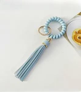 Close-up of light blue telephone wire key ring with a long leather tassel and gold metal ring