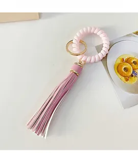 Detailed macro view of pink tassel keychain with golden ring and spiral coil charm