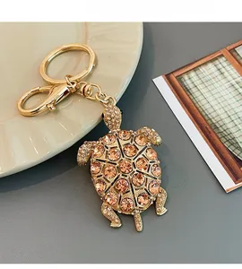 Dettaglio del portachiavi a tartaruga dorata con strass arancioni e chiusura a moschettone