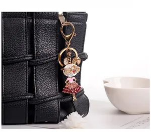 Close-up of a sparkling rhinestone bunny keychain hanging on a black woven handbag