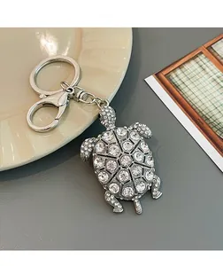 Dettaglio di un portachiavi a forma di tartaruga con strass bianchi e chiusura a moschettone