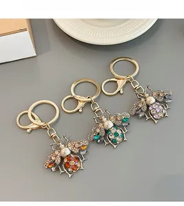 Detailed macro view of three vibrant rhinestone bee keychains in orange, green and purple