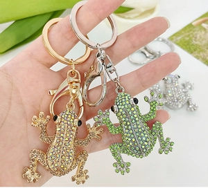Detail of sparkling rhinestone-encrusted frog keychains in gold and green metal finish