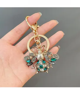 Close-up of golden bee keychain with colorful rhinestones on a dark background