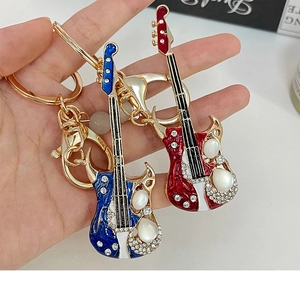 Détails des porte-clés guitare en émail rouge et bleu avec des cristaux brillants