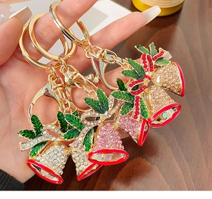 Close-up of golden Christmas bell keychain with rhinestones and red bow detail