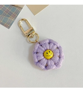Detail view of purple crochet flower keychain with a yellow smiley face bead and gold clasp
