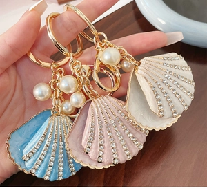 Detail of enamel seashell keychains with rhinestones and pearls in three colors
