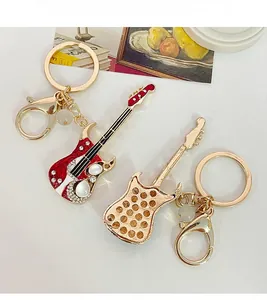 Détail artistique des porte-clés guitare électrique avec strass et émail rouge brillant