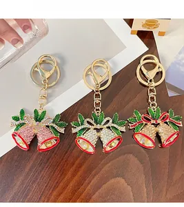Close-up of sparkling rhinestone Christmas bell keychain with green enamel leaf detail