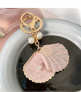 Detail of pink enamel shell keychain with pearls and crystals on a luxury golden base